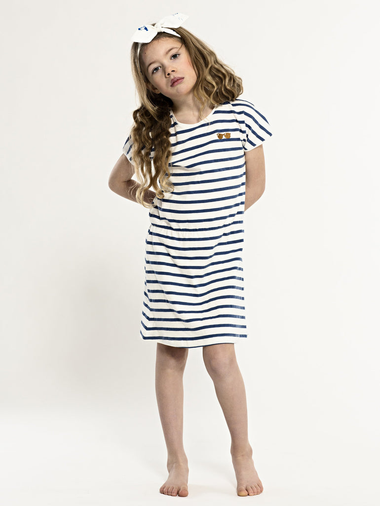 SS19 spring collection from One We Like made of 100% organic cotton. Dress with short sleeves and stripes. Sunglasses at right hand side of chest.